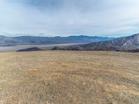 a person on a motor bike on top of a mountain looking down at mountains and a large amount of dirt