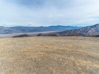 a person on a motor bike on top of a mountain looking down at mountains and a large amount of dirt