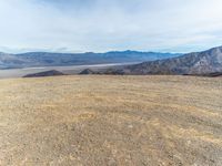 a person on a motor bike on top of a mountain looking down at mountains and a large amount of dirt