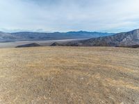 a person on a motor bike on top of a mountain looking down at mountains and a large amount of dirt