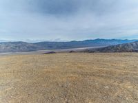 a person on a motor bike on top of a mountain looking down at mountains and a large amount of dirt