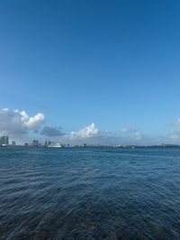 a boat floating in the open ocean by a city with tall buildings in the background