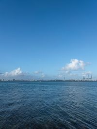 a boat floating in the open ocean by a city with tall buildings in the background