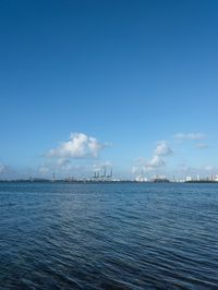 a boat floating in the open ocean by a city with tall buildings in the background