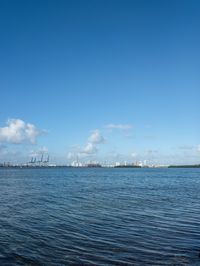 a boat floating in the open ocean by a city with tall buildings in the background