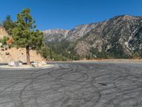 an empty road in front of the mountains with trees on either side and rocks piled on the top