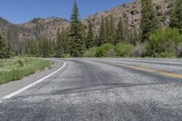 a highway passing through the middle of mountains and forest on its side with trees on the other side