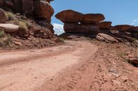 there is a dirt road that goes between two large rocks and another rocky, very large stone formation