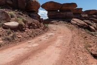 there is a dirt road that goes between two large rocks and another rocky, very large stone formation