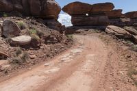 there is a dirt road that goes between two large rocks and another rocky, very large stone formation