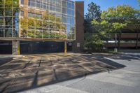 an empty parking lot that is outside in the daytime hours with trees around it and the building has windows