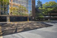 an empty parking lot that is outside in the daytime hours with trees around it and the building has windows