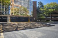 an empty parking lot that is outside in the daytime hours with trees around it and the building has windows