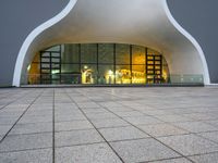 a building with glass doors and a stone floor in front of it at night with a fire hydrant on a concrete sidewalk