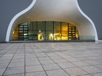 a building with glass doors and a stone floor in front of it at night with a fire hydrant on a concrete sidewalk