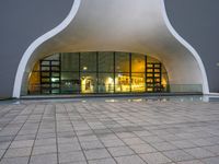 a building with glass doors and a stone floor in front of it at night with a fire hydrant on a concrete sidewalk