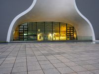 a building with glass doors and a stone floor in front of it at night with a fire hydrant on a concrete sidewalk