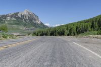 a road with trees on both sides of it and mountains in the background behind it