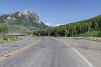 a road with trees on both sides of it and mountains in the background behind it