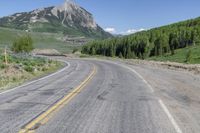 a road with trees on both sides of it and mountains in the background behind it