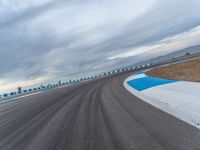 Daytime Race on Curved Road: Cloudy Skies