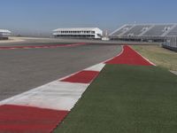 an empty track at a motorsports club with some red and white stripeing on it