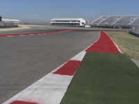 an empty track at a motorsports club with some red and white stripeing on it