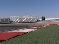an empty track at a motorsports club with some red and white stripeing on it