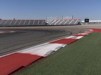 an empty track at a motorsports club with some red and white stripeing on it