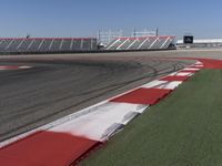 an empty track at a motorsports club with some red and white stripeing on it