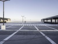 a empty parking lot with street lamps in the background - and a plane landing at the far end