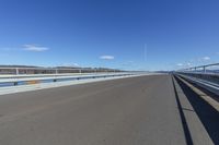 an empty road under a clear blue sky and white clouds in the distance is the highway on which there is no traffic or traffic