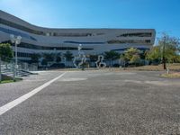 a parking lot next to a large building with glass windows and sculptures in front of it