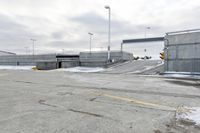 a snow covered parking lot with a bridge crossing in the back ground and no one standing or sitting