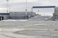 a snow covered parking lot with a bridge crossing in the back ground and no one standing or sitting