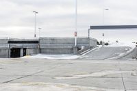 a snow covered parking lot with a bridge crossing in the back ground and no one standing or sitting