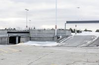 a snow covered parking lot with a bridge crossing in the back ground and no one standing or sitting