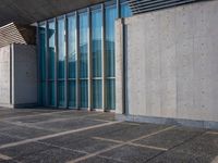 a sidewalk that has several glass doors next to it with buildings in the background behind