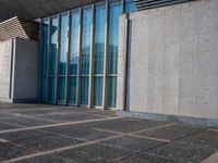 a sidewalk that has several glass doors next to it with buildings in the background behind