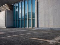 a sidewalk that has several glass doors next to it with buildings in the background behind