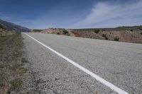 a lone motorcycle parked on the side of an empty road near mountains and hills in the background