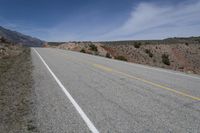 a lone motorcycle parked on the side of an empty road near mountains and hills in the background