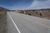 a lone motorcycle parked on the side of an empty road near mountains and hills in the background