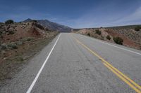 a lone motorcycle parked on the side of an empty road near mountains and hills in the background