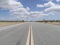 a long empty street that goes through the desert as clouds are rolling in the sky