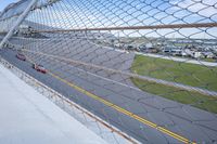 a car racing on a track by a fence with other cars at the finish line