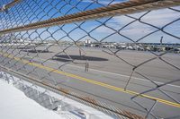 a close up of a tarmac near a chain link fence and plane landing strip