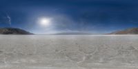 the beach is vast with low clouds in the sky and a big sun above the hill