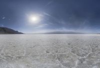 an empty open area on a sunny day with a bright sun behind the mountains and clouds