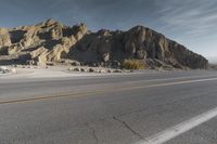 a long street with mountains in the background and rocks at the edge, both yellow